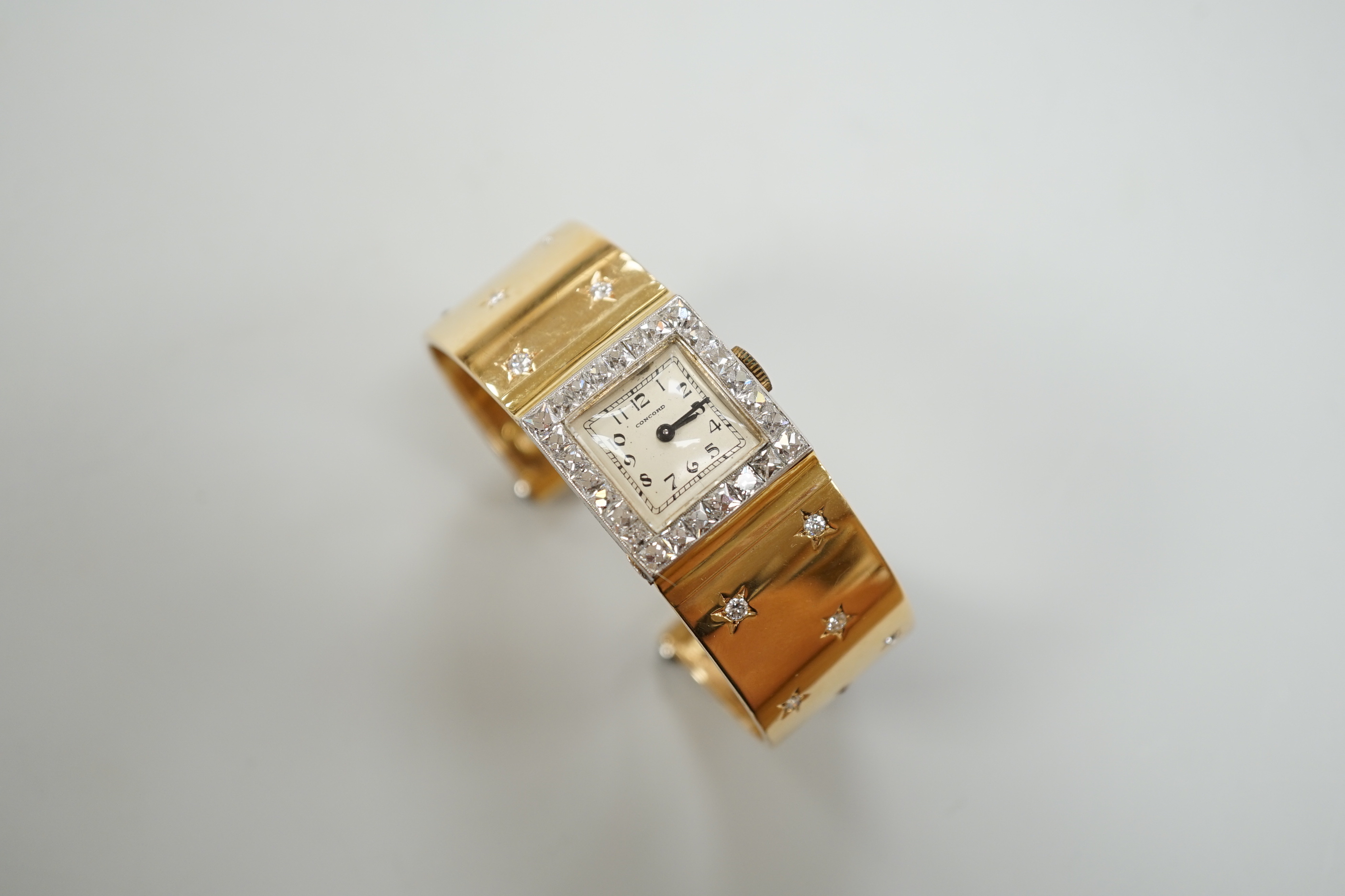A yellow metal and diamond set Concorde manual wind open bracelet watch, with diamond set bezel and bracelet, gross weight 47.8 grams.